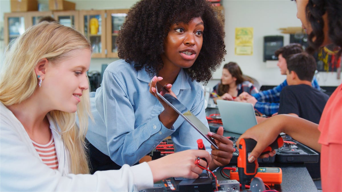 A teacher helping students build a robotic vehicle during a hands-on science lesson