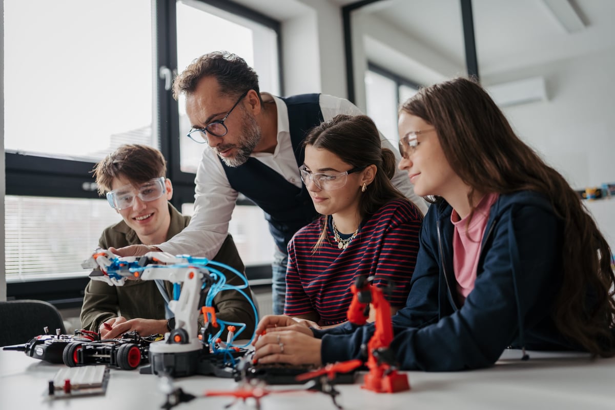 High school students working together on a robotics project with their teacher